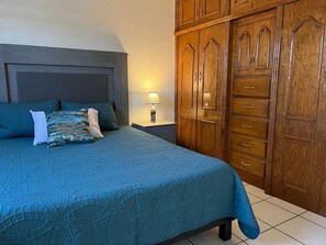 Un dormitorio con cama, mesita de noche y armario de madera.