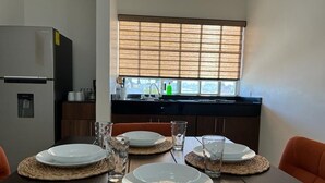 A dining table set with plates and glasses, a refrigerator, a window with blinds, and a kitchen counter. - Casa Rebeca3 Complete, ideal for large groups, work teams, vacations, etc. (Chihuahua)