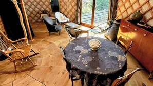 Et yurts indre med et rundt bord, stole, en sofa og et træskab.