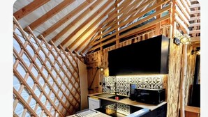A compact kitchen with a wooden ceiling, a black countertop, and a tiled backsplash. - The owl's yurt (Floreffe)