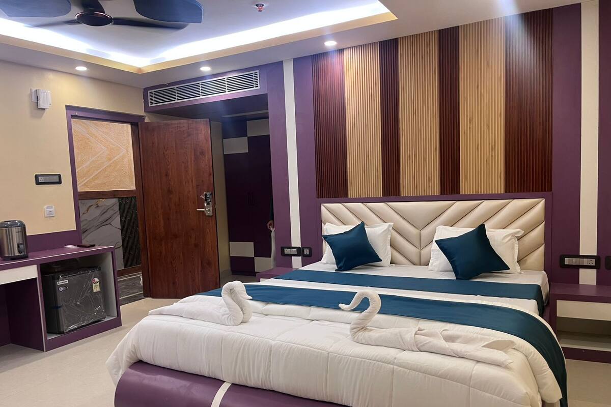 A modern hotel room with a large bed, a desk, and a wardrobe.