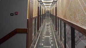 A long, narrow hallway with a polished marble floor, recessed lighting, and a patterned wall. - Royal Classic Hotel (Digha)