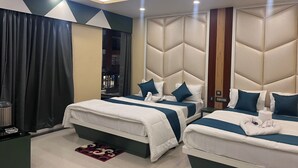 A hotel room with two beds, a large window, a ceiling fan, and a view of the outside. - Royal Classic Hotel (Digha)