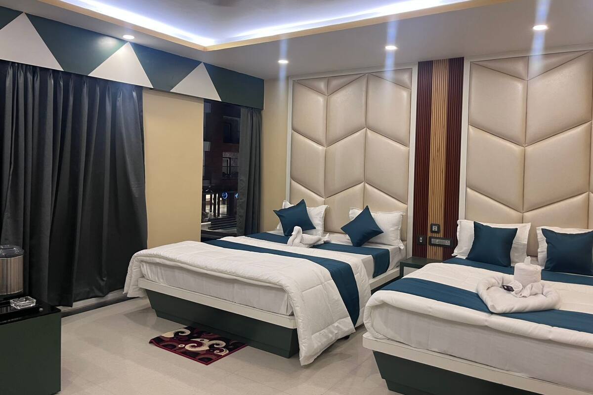 A hotel room with two beds, a large window, a ceiling fan, and a view of the outside.