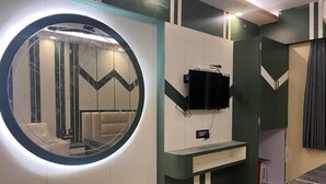 A modern room with a circular mirror, a mounted TV, and a sofa. - Royal Classic Hotel (Digha)