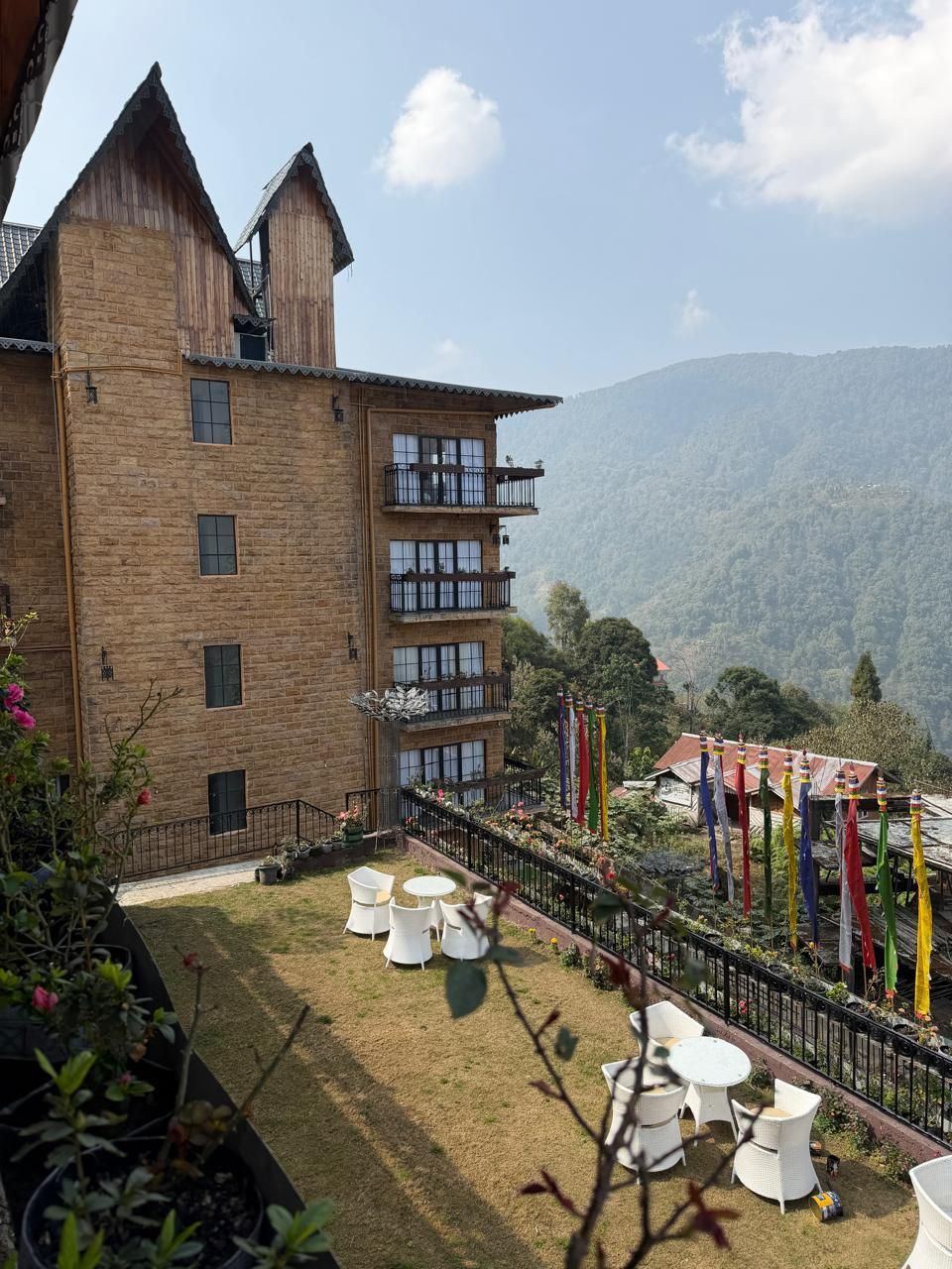 A multi-story building with a brick facade, balconies, and a grassy courtyard with outdoor seating.