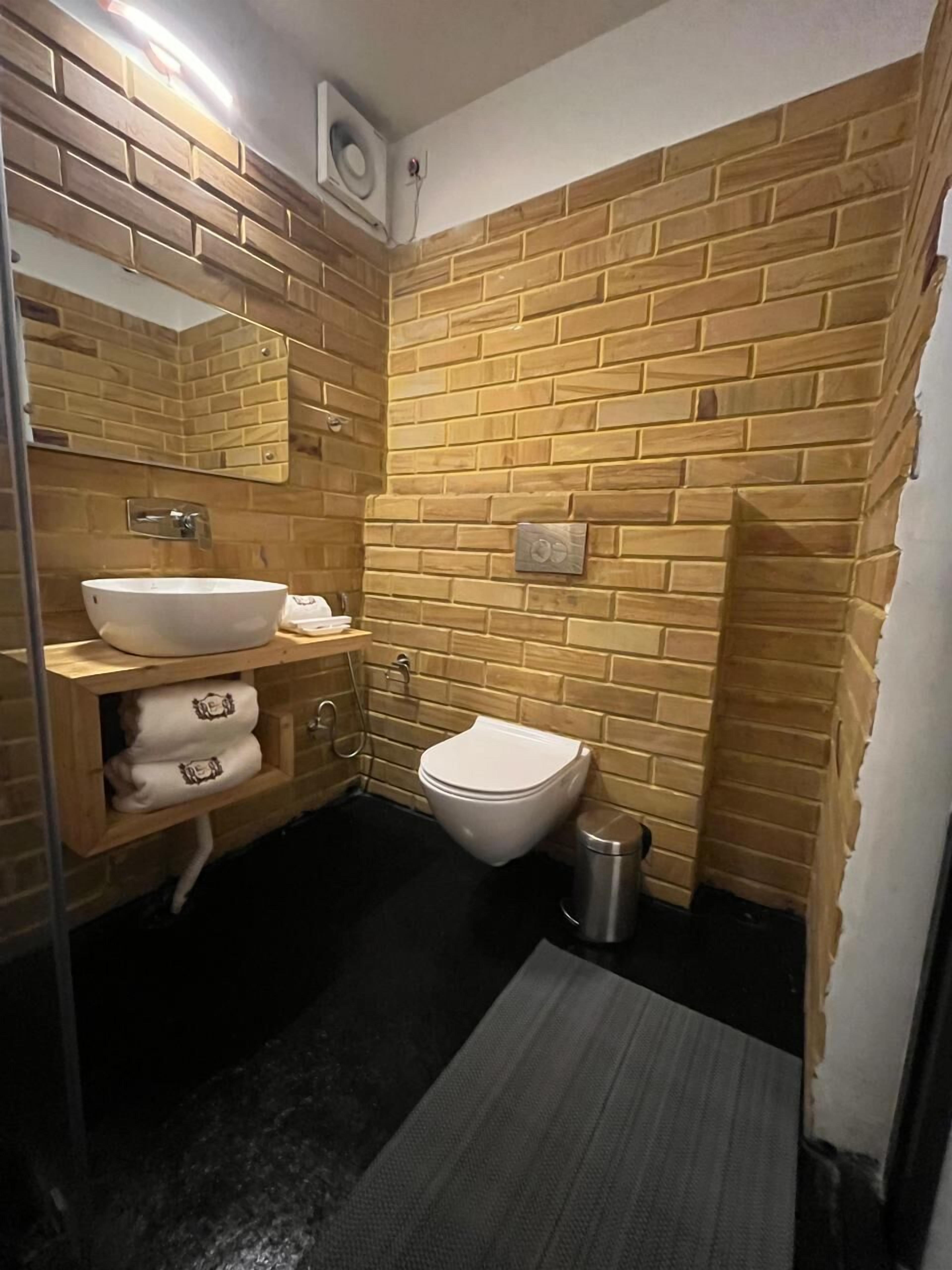 A bathroom with a white sink, a toilet, and a trash bin.