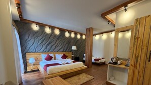 A bedroom with a bed, wooden furniture, a stone wall, and a wooden cabinet. - Evri Hotels & Resorts (Kolakham)