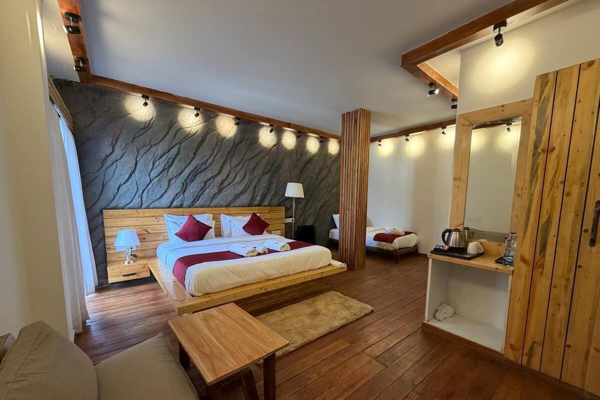 A bedroom with a bed, wooden furniture, a stone wall, and a wooden cabinet.