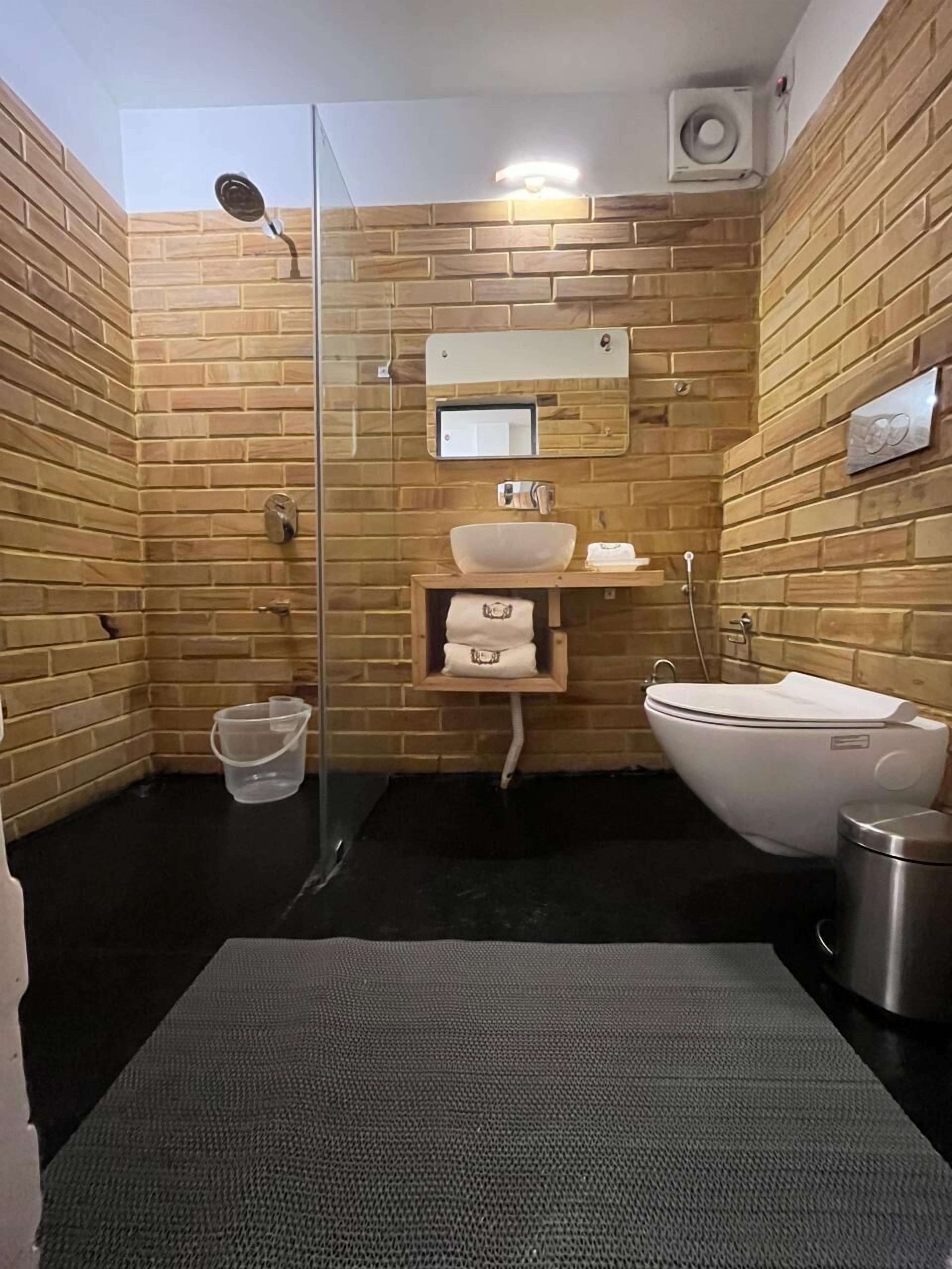 A bathroom with a shower, toilet, sink, and a towel rack.