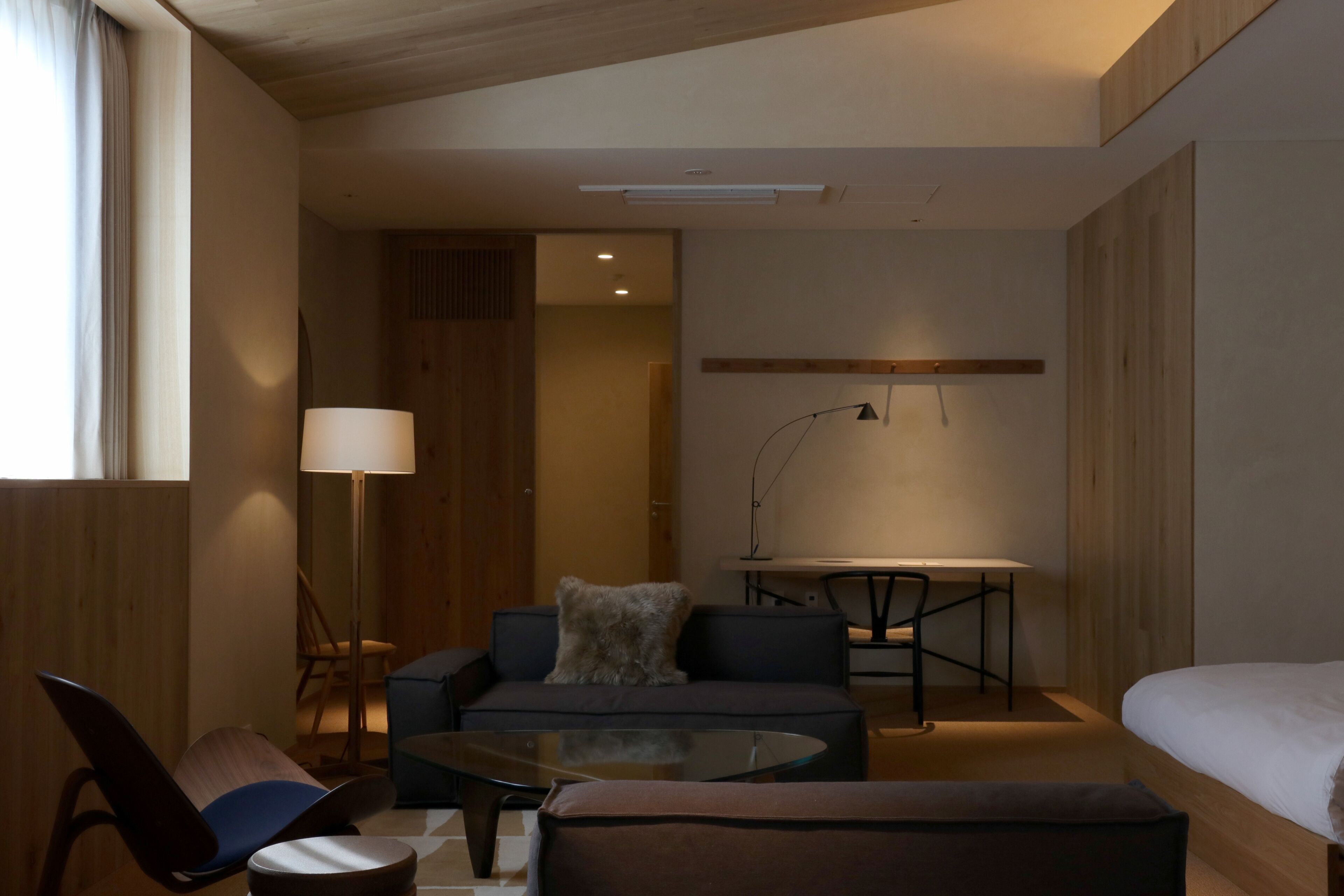 Una habitación de hotel moderna con sofá, sillón, mesita y cama.