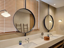 Un baño con dos lavamanos, espejos redondos y un mueble de tocador de madera.