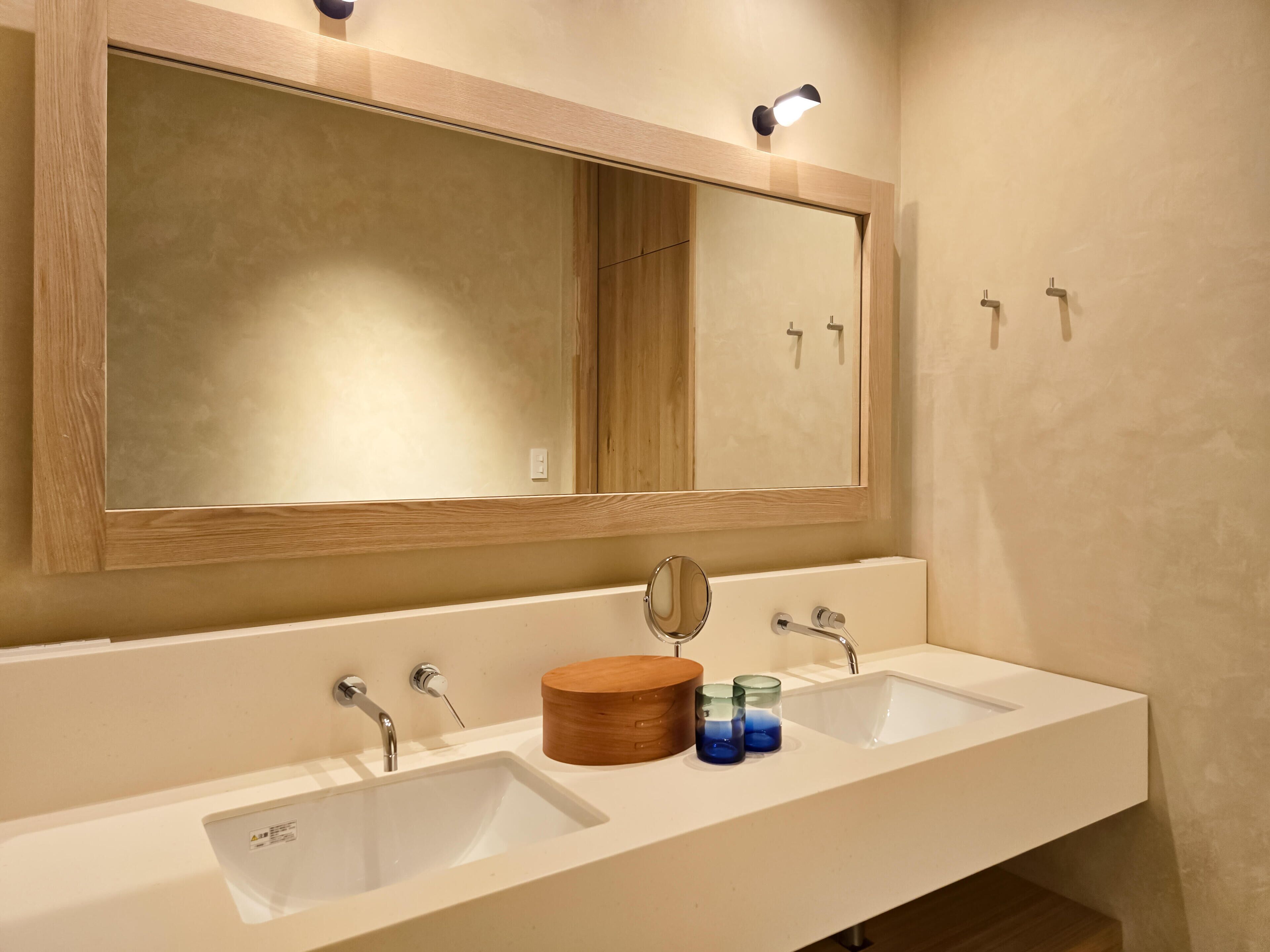 A bathroom with two sinks, a large mirror, and a wooden vanity.