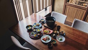 A wooden dining table with various dishes and a large bowl, surrounded by chairs. - HACIENDA KARUIZAWA HOTEL (Karuizawa)