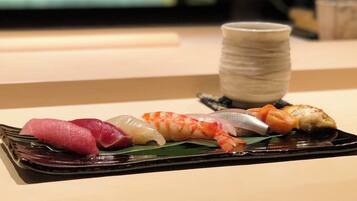 A black rectangular plate with various sushi pieces on a table.