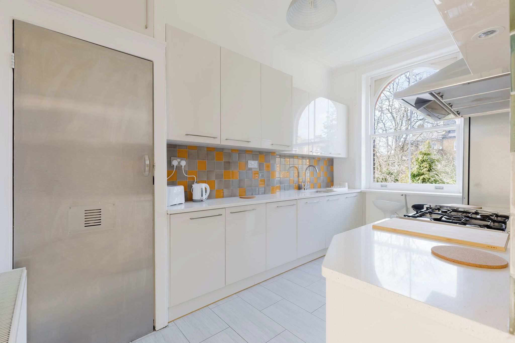 A modern kitchen with white cabinetry, a gas stove, and a window providing a view of the outside.