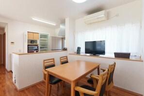 A compact kitchen with a dining area, built-in cabinets, a microwave, and a television. - ASHIBINA INN (Ishigaki)