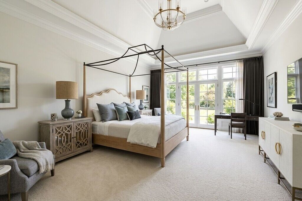 Een slaapkamer met een hemelbed, een bureau en een stoel.