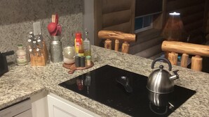 Una cocina con encimeras de granito, una placa de inducción negra, utensilios de madera y un hervidor.