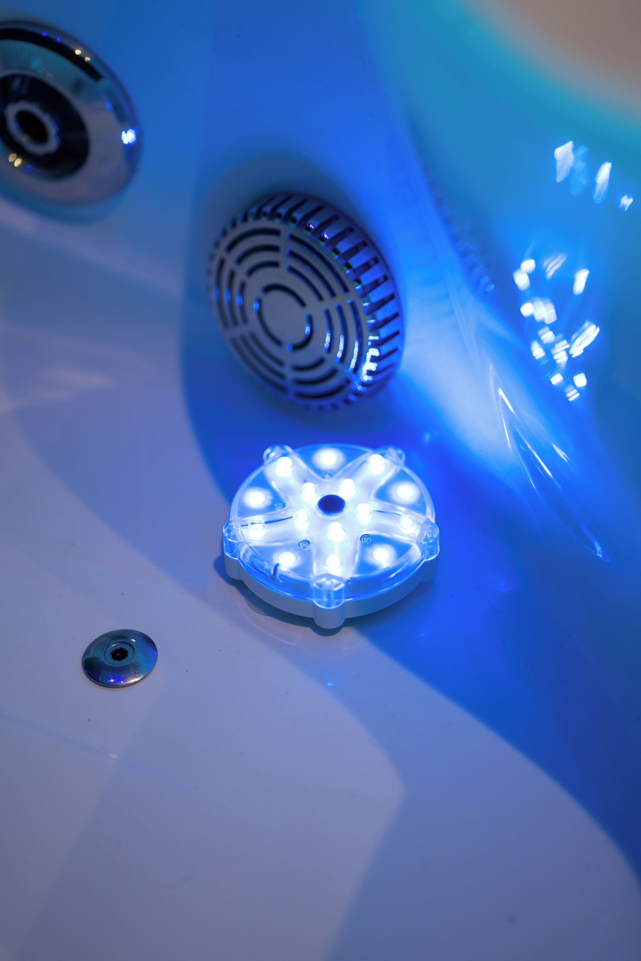 Un baño con lavamanos, rejilla de desagüe y ventilador.