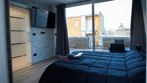 Ein Schlafzimmer mit einem großen Bett, einem an der Wand montierten Fernseher und einem Balkon mit einem Stuhl.