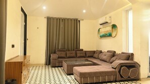 A living room with a sectional sofa, a glass coffee table, and a patterned floor.