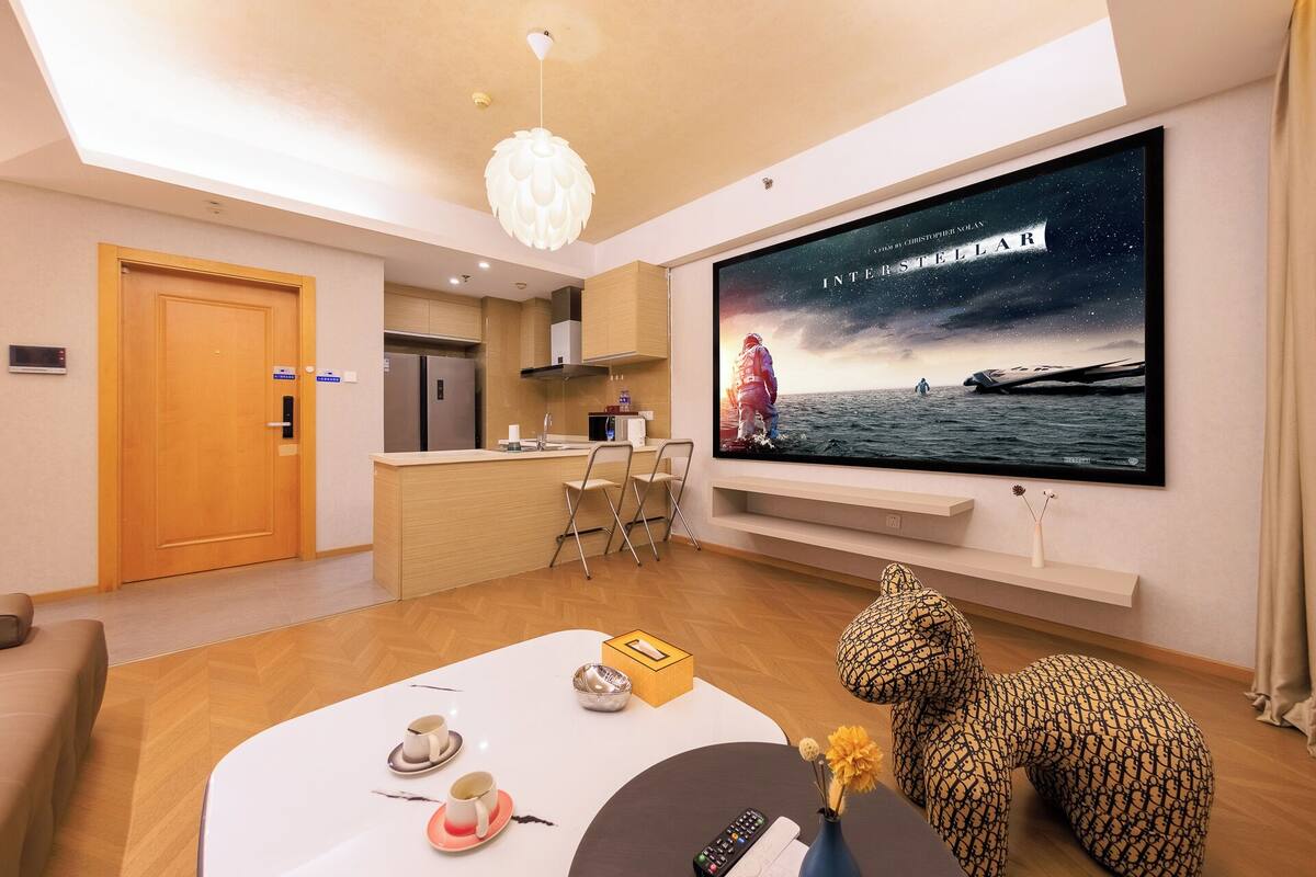 Un salon moderne doté d’un grand téléviseur à écran plat, d’un coin cuisine et d’un espace repas.