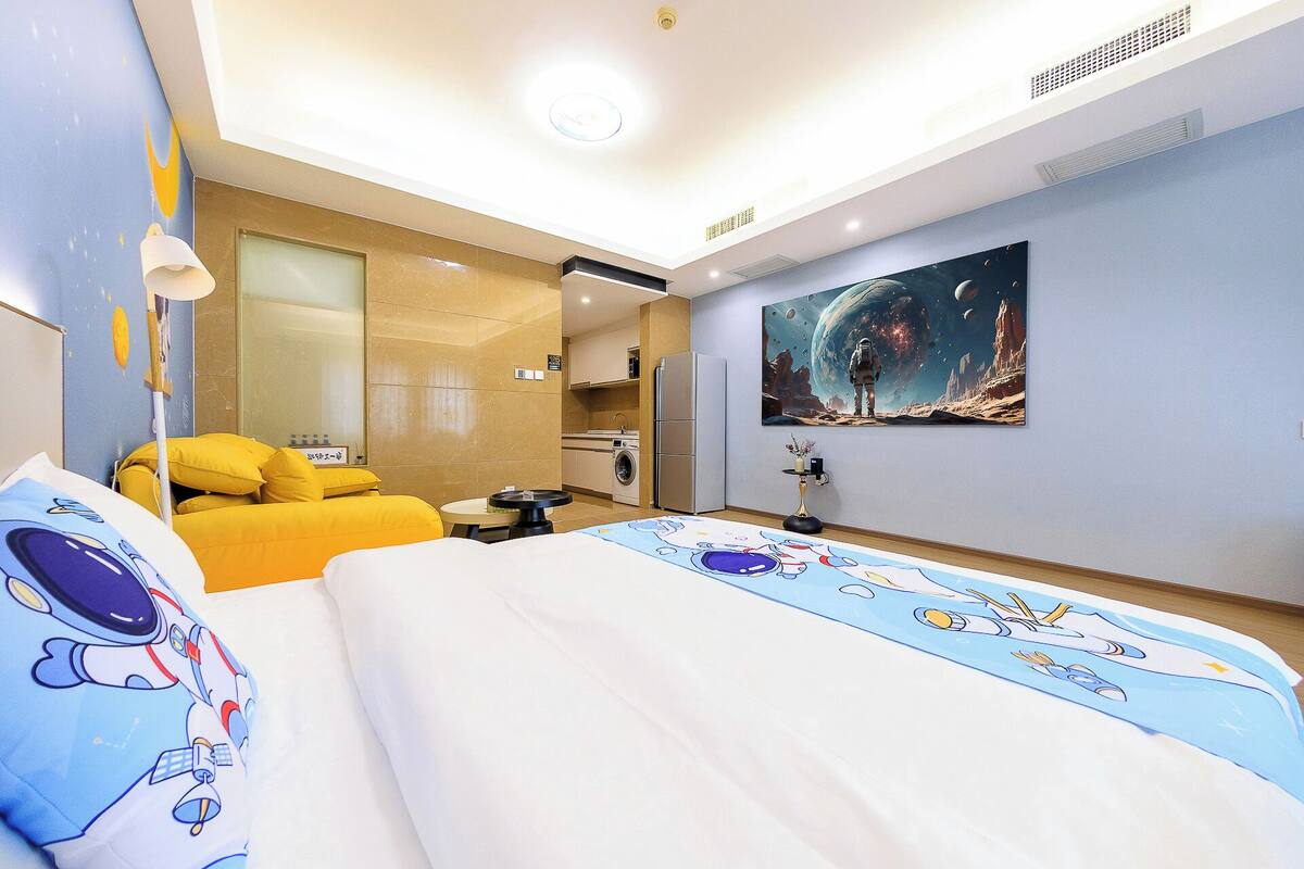 Une chambre d’hôtel avec un lit, un canapé, un tableau représentant l’espace et une kitchenette.