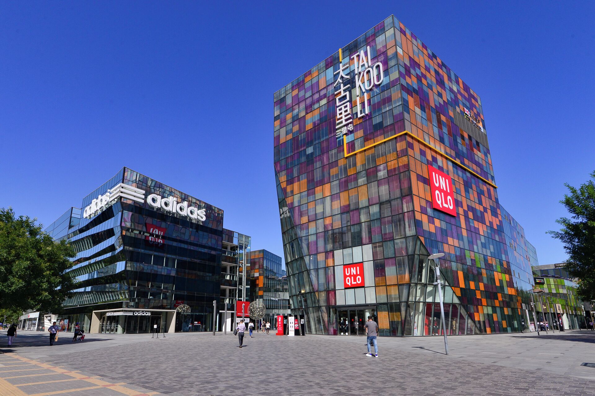 Un bâtiment moderne à la façade colorée, sur lequel on peut voir une enseigne bien visible d’Adidas et de UNIQLO.
