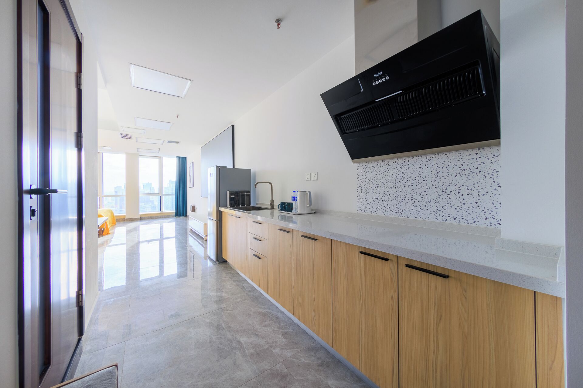 A modern kitchen with a black range hood, wooden cabinets, and a stainless steel sink.