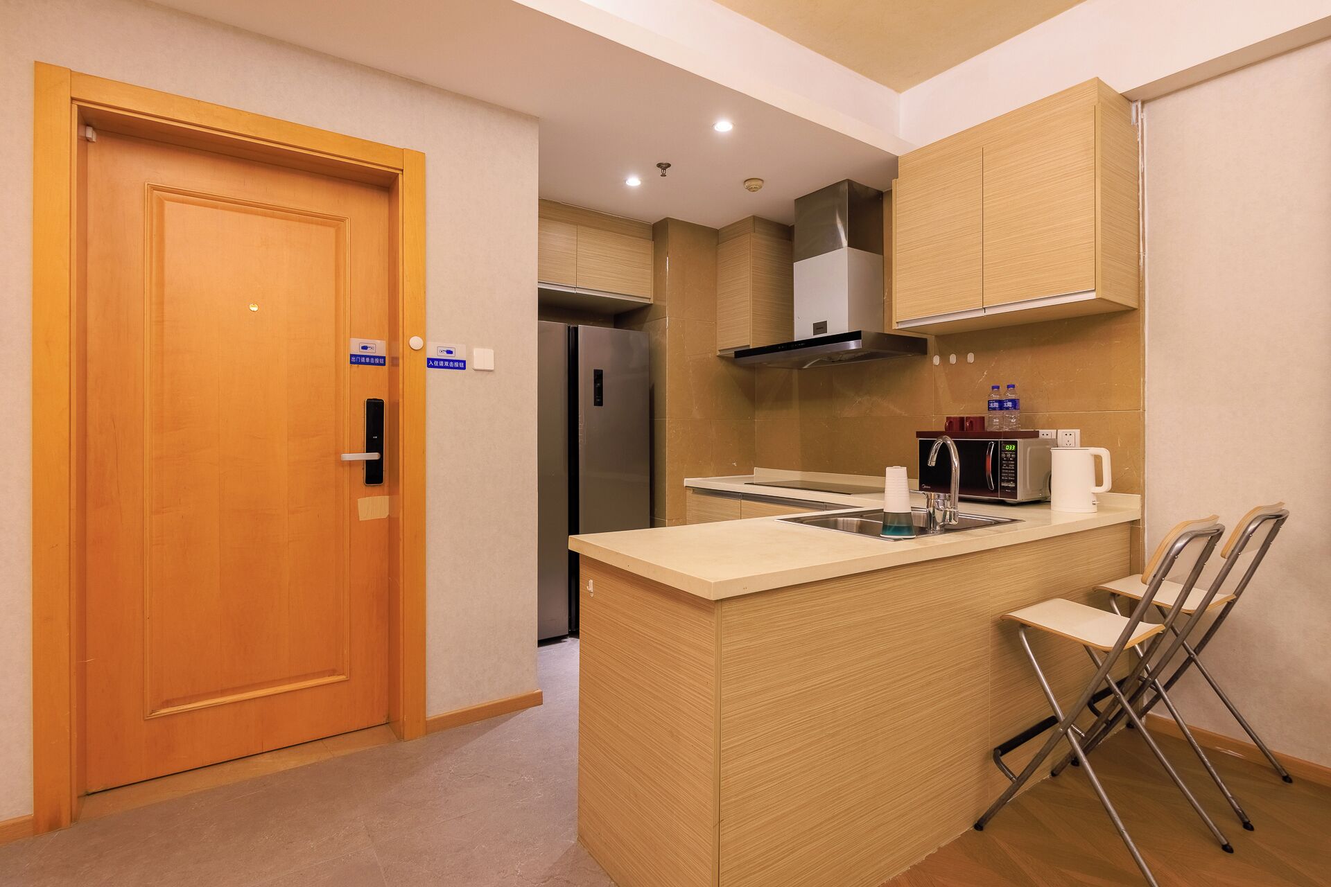 A compact kitchen with a wooden door, a built-in stove, a microwave, and a coffee maker.