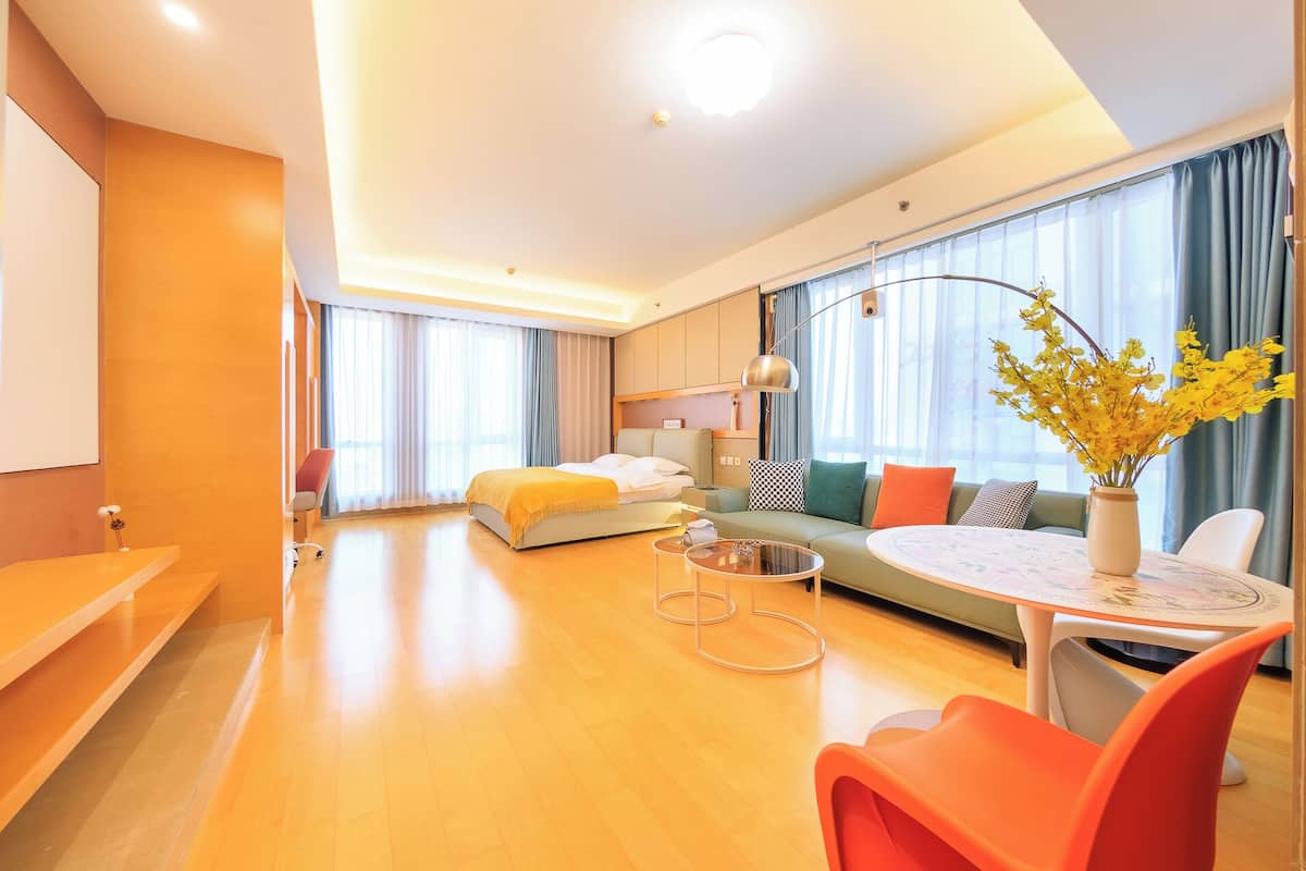 Une chambre d’hôtel moderne équipée d’un lit, d’un canapé, d’une table à manger et d’un vase de fleurs.