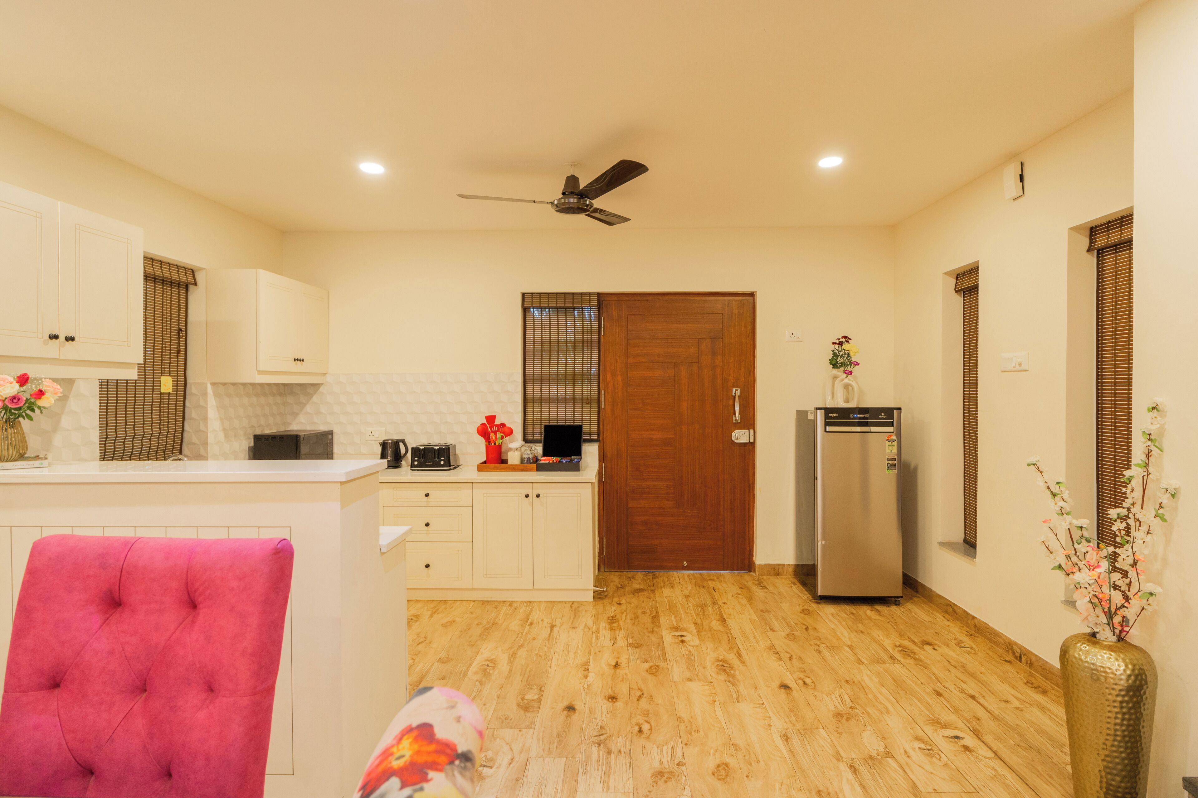A modern kitchen with a wooden floor, a ceiling fan, and a refrigerator.