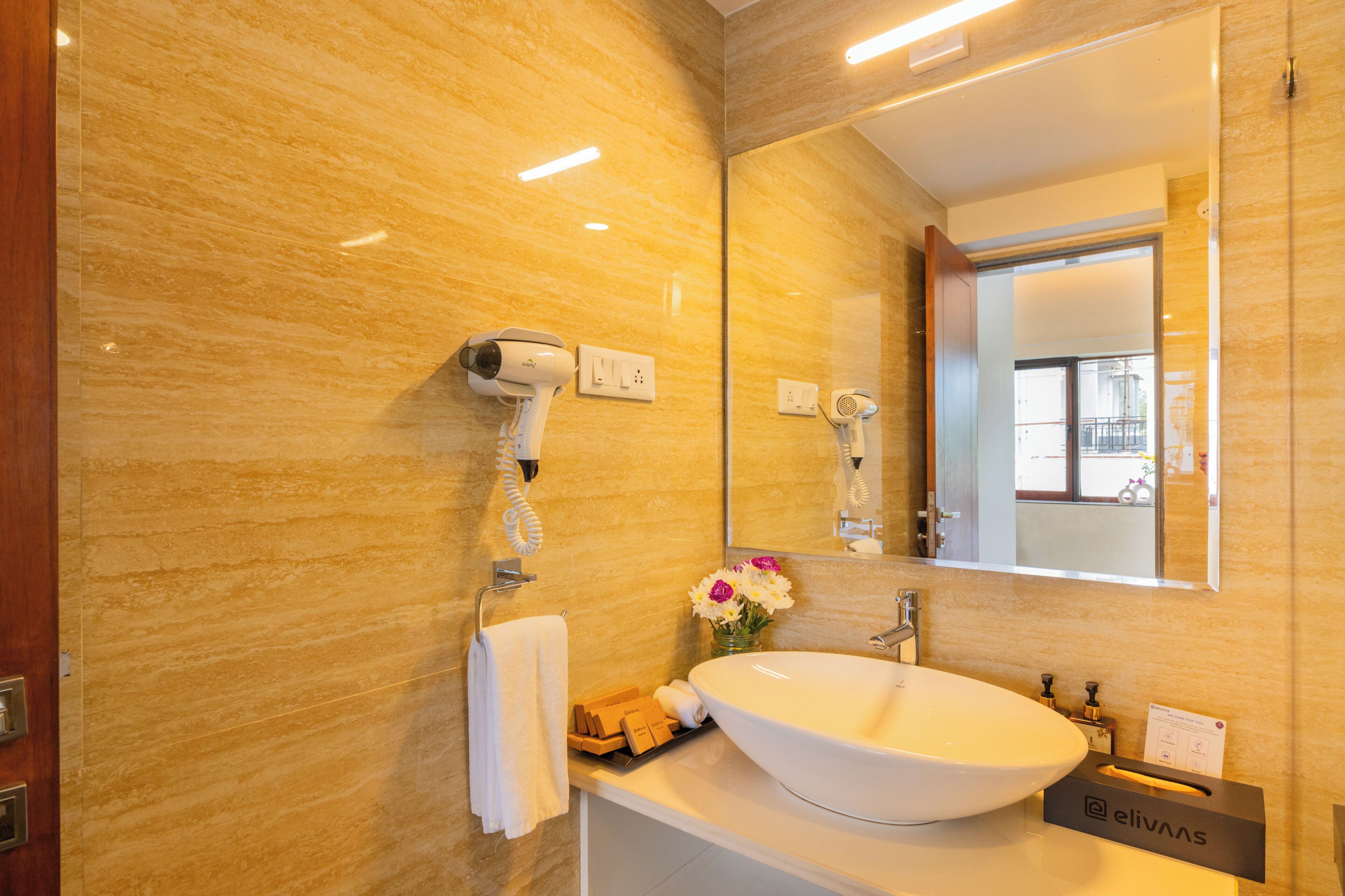 A bathroom with a white sink, a hairdryer, a towel, and a mirror.