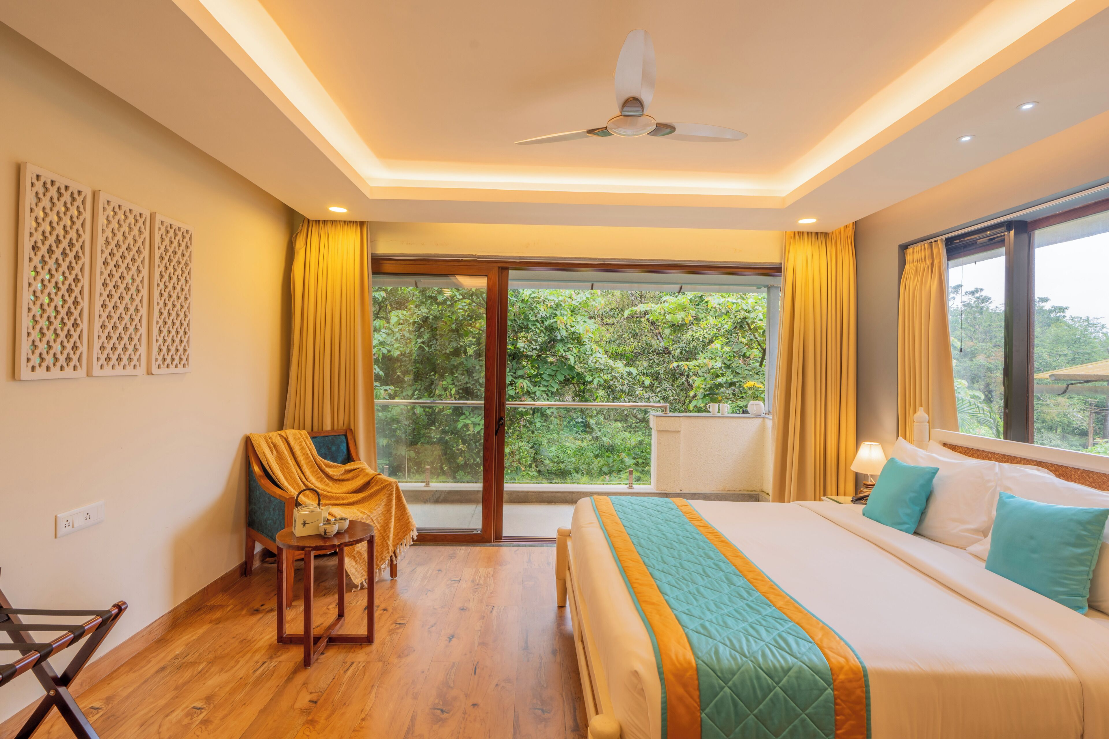 A bedroom with a bed, a chair, a table, a ceiling fan, and a window with curtains.
