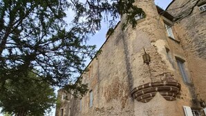 Un bâtiment rustique en pierre, doté d’une tour, d’une terrasse et d’un jardin.