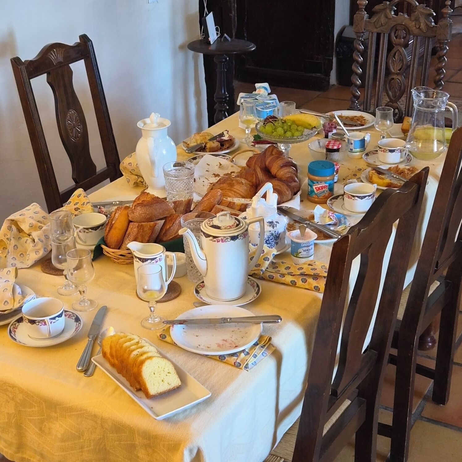 A dining table set with various breakfast items including bread, pastries, and condiments.