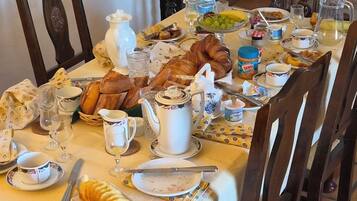 A dining table set with various breakfast items including bread, pastries, and condiments.