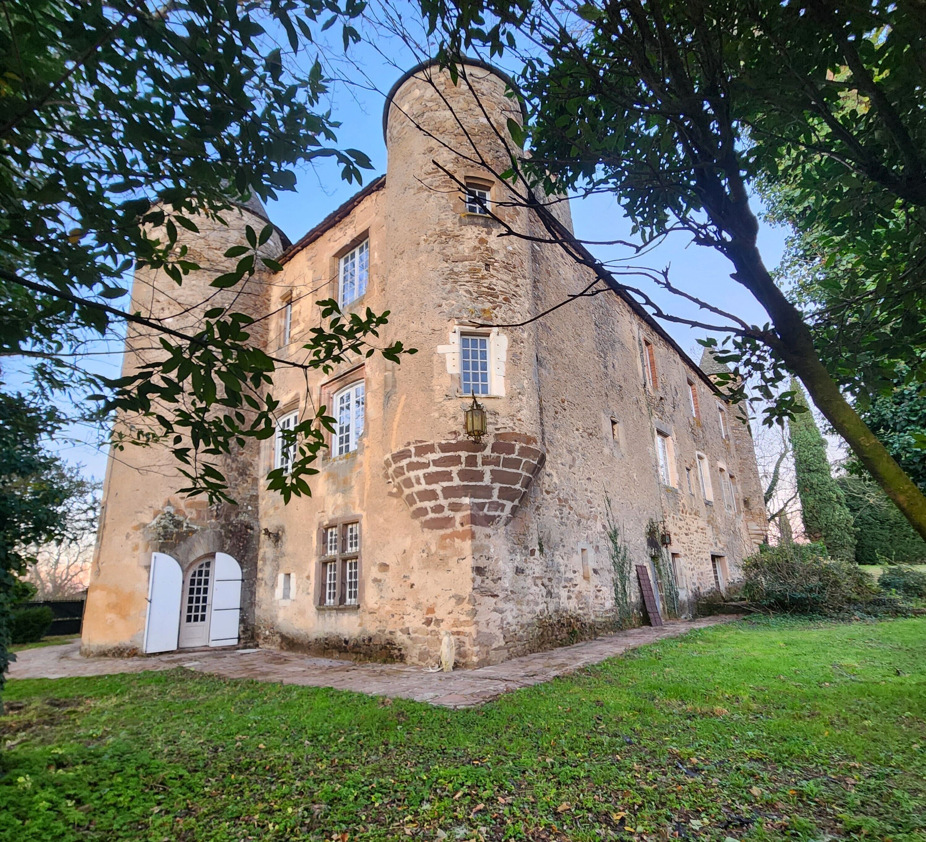 Un edificio histórico de piedra con una torre central, ventanas de arco y una pequeña puerta.