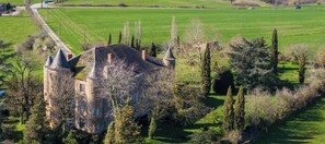 A castle with multiple towers, surrounded by a well-maintained lawn and trees. - Château de Trévien (Trévien)