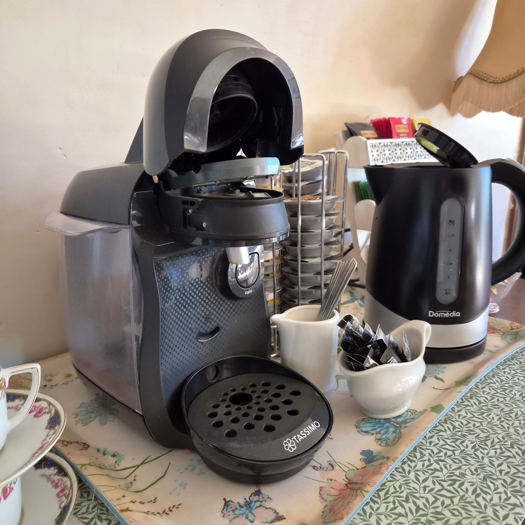 A coffee maker, a mug, and a stack of plates on a table.