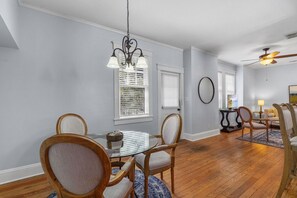 A dining area with a chandelier, wooden chairs, a glass table, and a ceiling fan. - Upper Carriage House at Wayne Estate (Savannah)