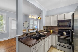 A kitchen with a granite countertop, stainless steel appliances, and pendant lighting. - Upper Carriage House at Wayne Estate (Savannah)