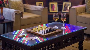 Una habitación con un tablero de ajedrez, dos copas de vino y un vitral.