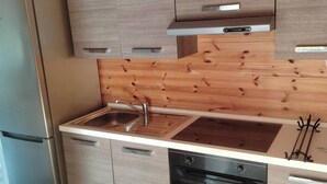 A modern kitchen with wooden paneling, stainless steel appliances, and a built-in oven.