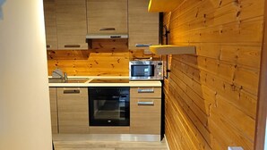 A modern kitchen with wooden walls, a built-in oven, and a microwave.