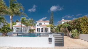 Un quartiere residenziale con piscina, edifici bianchi e palme.