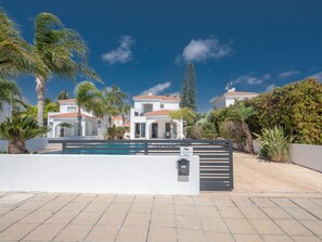 A residential area with a swimming pool, white buildings, and palm trees. - Ayia Napa Holiday Villa SV11 (Ayia Napa)