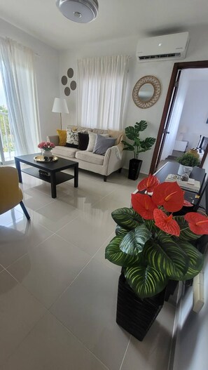 A living room with a sofa, coffee table, and potted plants. - Elegant Pool-View Apartment Near Punta Cana Beach (Punta Cana)