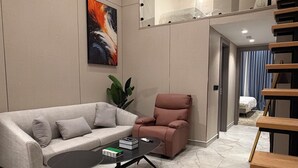 Ein modernes Wohnzimmer mit einer Couch, einem Couchtisch, einem Sessel und einer Treppe.
